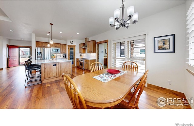 dining area with light wood finished floors, plenty of natural light, an inviting chandelier, and recessed lighting