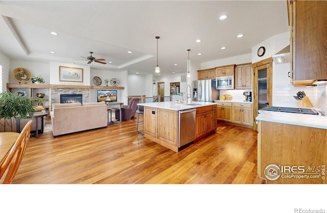 kitchen featuring stainless steel appliances, a tray ceiling, light countertops, and wall chimney range hood