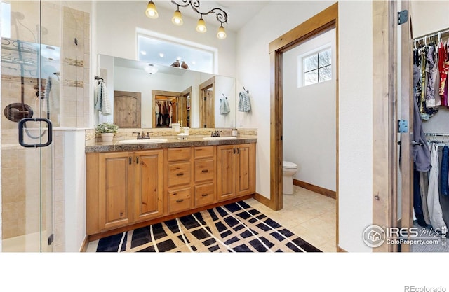 bathroom featuring a sink, a walk in closet, and a shower stall