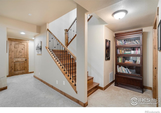 staircase featuring carpet flooring, visible vents, and baseboards