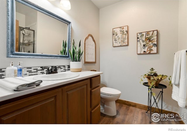 bathroom with tasteful backsplash, toilet, wood finished floors, an enclosed shower, and vanity