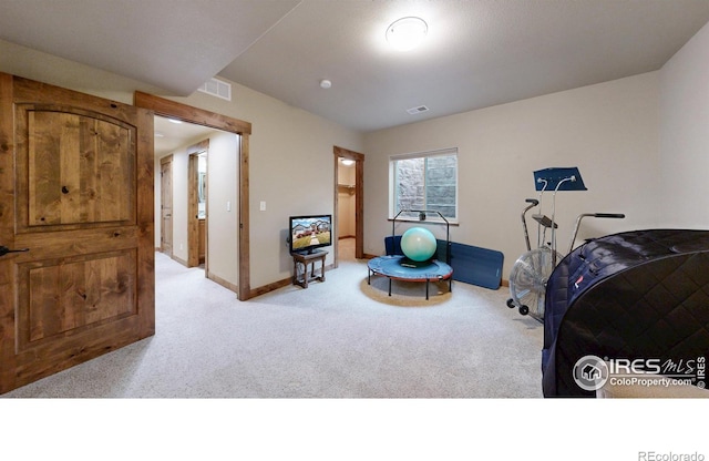 workout room with baseboards, visible vents, and light colored carpet