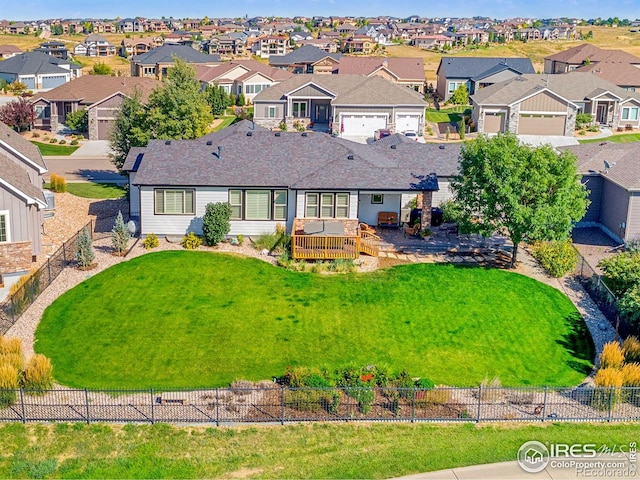 view of front of house featuring a garage, a residential view, a front yard, and fence private yard