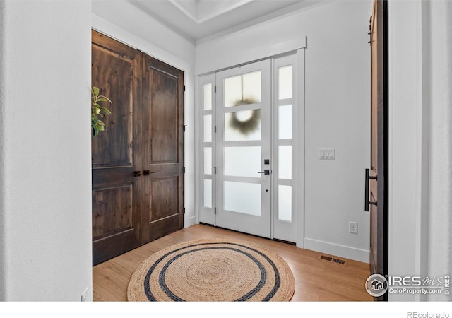 foyer entrance with a healthy amount of sunlight, visible vents, baseboards, and wood finished floors