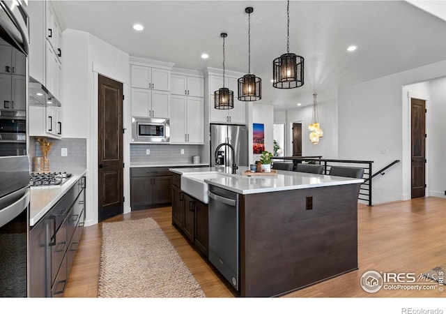 kitchen featuring stainless steel appliances, light countertops, a sink, and light wood finished floors