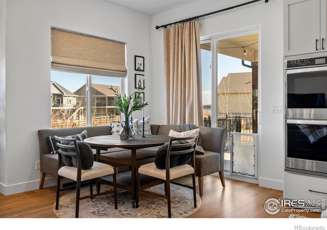 dining area with baseboards, light wood-type flooring, and a healthy amount of sunlight