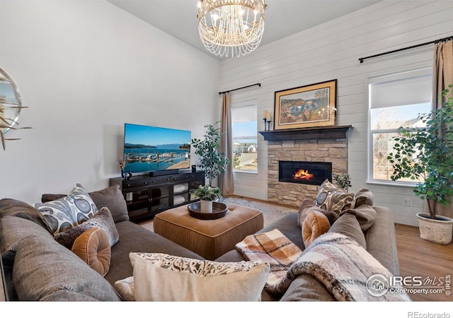 living area with a chandelier, a fireplace, high vaulted ceiling, and wood finished floors