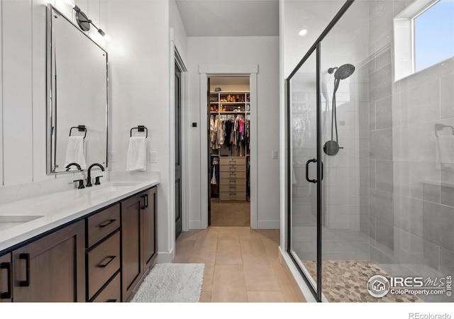 bathroom featuring double vanity, a stall shower, tile patterned floors, a spacious closet, and a sink