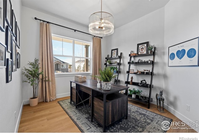 office area featuring an inviting chandelier, baseboards, and wood finished floors