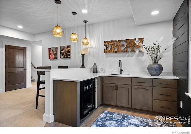 kitchen with wine cooler, recessed lighting, a sink, a peninsula, and a kitchen breakfast bar