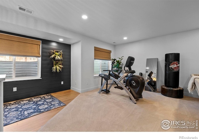 exercise room featuring recessed lighting, visible vents, wooden walls, wood finished floors, and baseboards