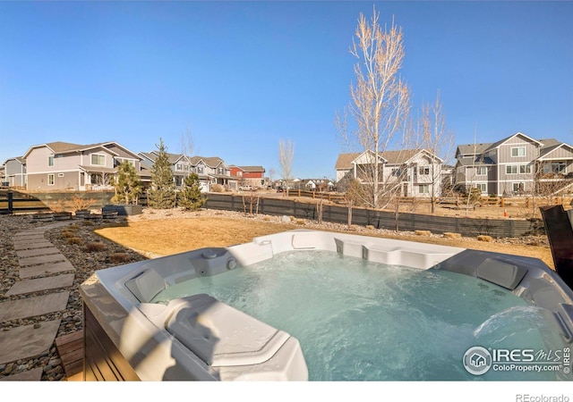 view of swimming pool featuring a hot tub, a residential view, and fence