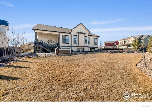 back of property with stairway, fence, and a lawn