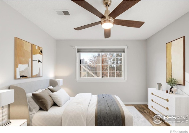 bedroom with a ceiling fan, baseboards, visible vents, and wood finished floors