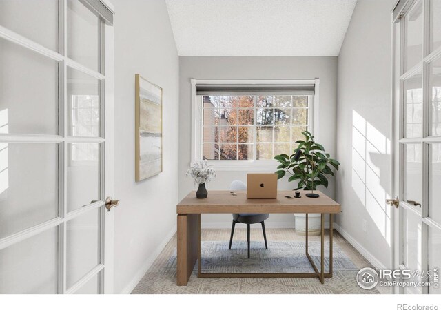 office featuring lofted ceiling, a textured ceiling, and baseboards