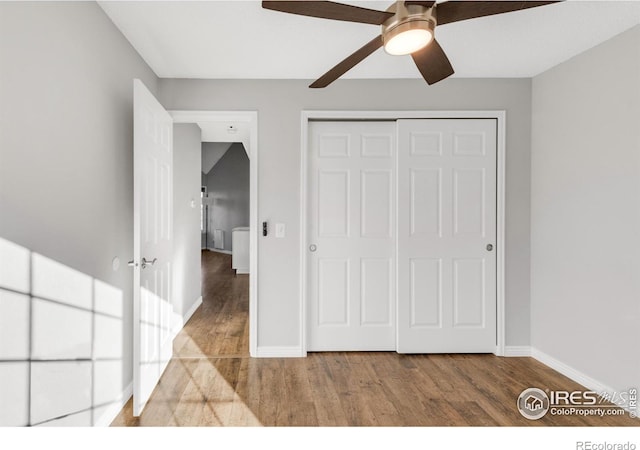 unfurnished bedroom featuring a closet, ceiling fan, baseboards, and wood finished floors