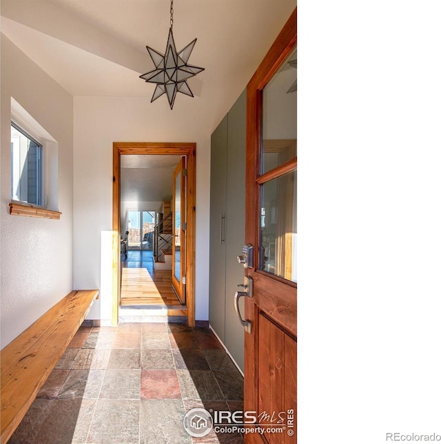 corridor with stone finish flooring, stairway, and baseboards