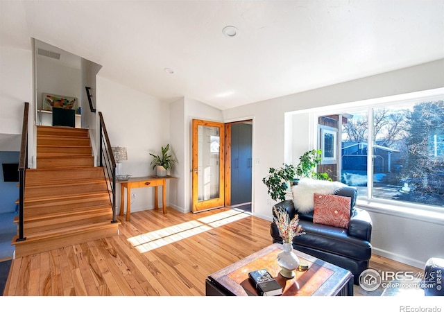 living area featuring lofted ceiling, visible vents, stairway, and wood finished floors