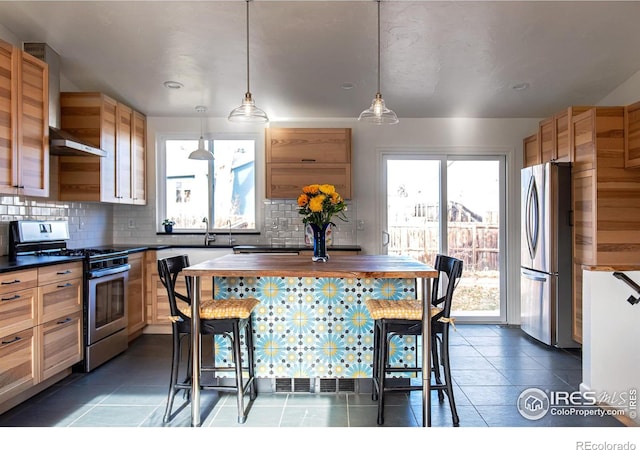 kitchen featuring dark countertops, wall chimney exhaust hood, appliances with stainless steel finishes, and tasteful backsplash