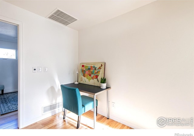 office area with baseboards, visible vents, and wood finished floors