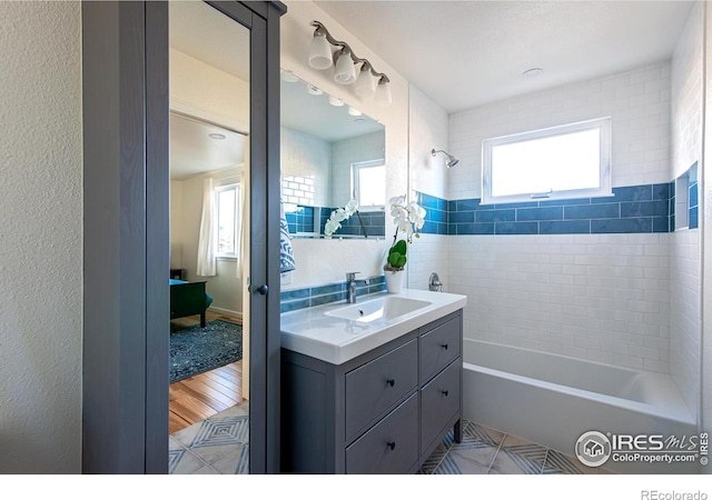 bathroom with a healthy amount of sunlight, tile patterned floors, washtub / shower combination, and vanity