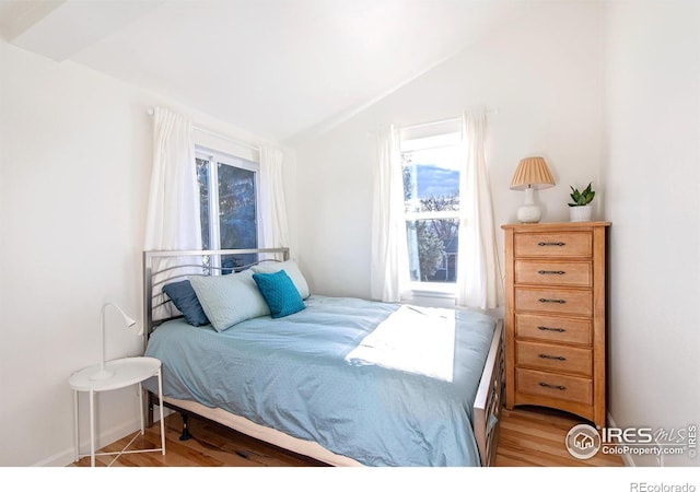 bedroom featuring lofted ceiling, light wood-type flooring, multiple windows, and baseboards