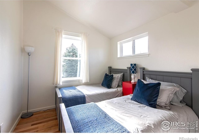 bedroom with lofted ceiling, wood finished floors, and baseboards