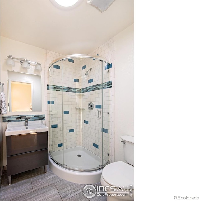 bathroom featuring toilet, a shower stall, and vanity