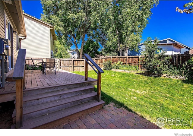 wooden deck with outdoor dining space, a fenced backyard, and a yard