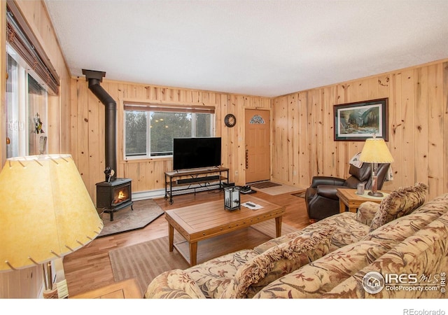 living room with a wood stove, wooden walls, and wood finished floors