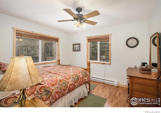 bedroom with a baseboard heating unit, ceiling fan, a textured ceiling, and wood finished floors