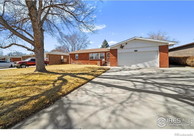 ranch-style house with driveway, brick siding, a front lawn, and an attached garage