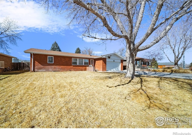 ranch-style house featuring brick siding, a front yard, fence, a garage, and driveway