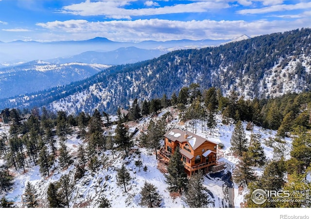 snowy aerial view featuring a mountain view and a view of trees