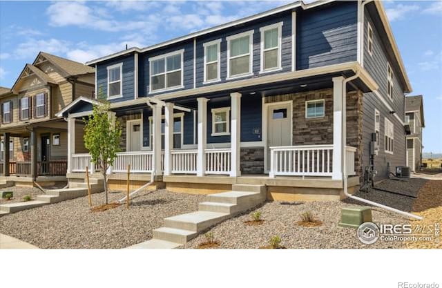 townhome / multi-family property featuring stone siding, cooling unit, and covered porch