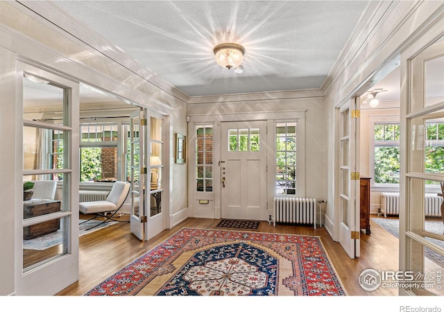 entryway featuring radiator heating unit, ornamental molding, and wood finished floors