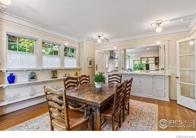 dining space featuring light wood finished floors, french doors, and ornamental molding