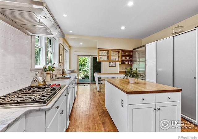 kitchen featuring wood counters, stainless steel gas cooktop, white cabinets, and a sink