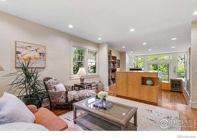 living area featuring beverage cooler, recessed lighting, light wood-style flooring, and a healthy amount of sunlight