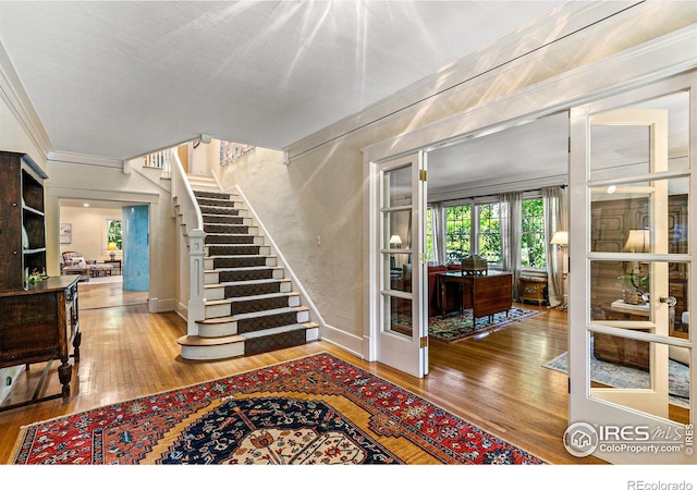 foyer featuring stairway, ornamental molding, and hardwood / wood-style floors