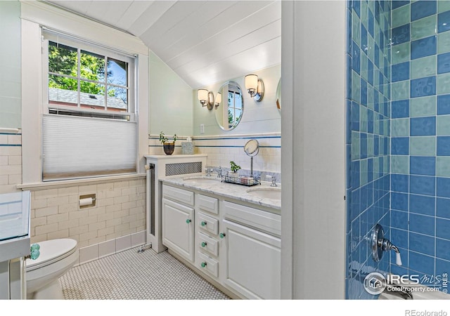 full bath with toilet, a sink, tile walls, vaulted ceiling, and tile patterned floors