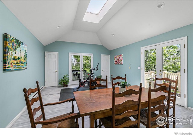 dining area with light wood-style floors, baseboards, lofted ceiling with skylight, and french doors