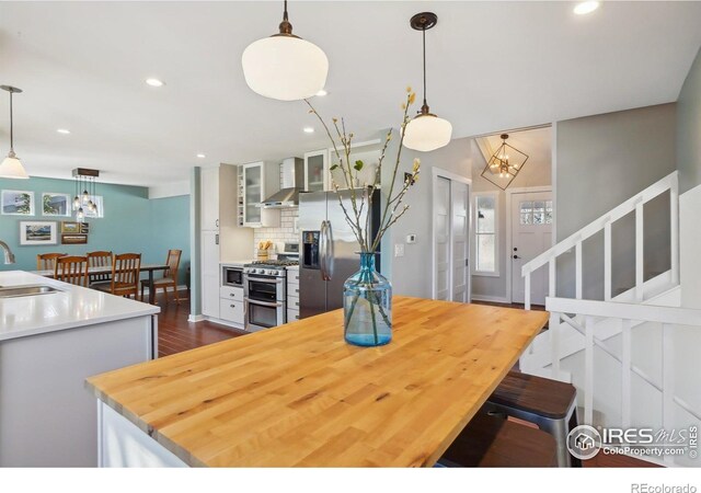 dining room with dark wood-type flooring, recessed lighting, and stairs