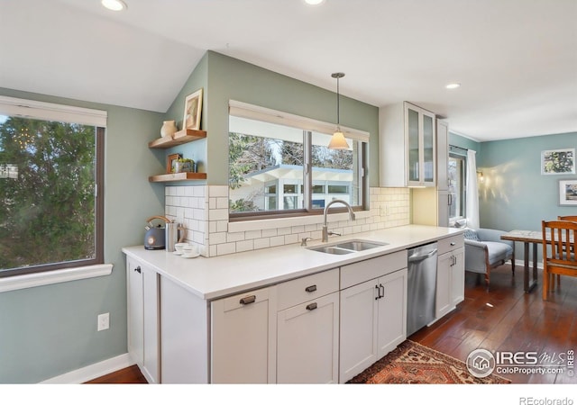 kitchen with decorative backsplash, glass insert cabinets, white cabinets, a sink, and dishwasher