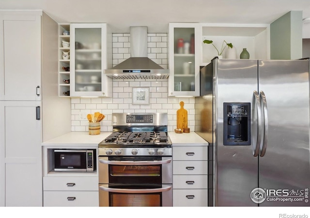 kitchen featuring wall chimney range hood, tasteful backsplash, stainless steel appliances, and light countertops