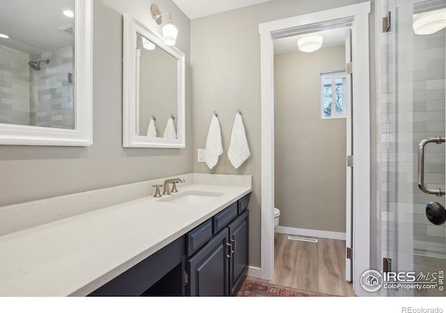 full bath featuring toilet, a stall shower, wood finished floors, and vanity