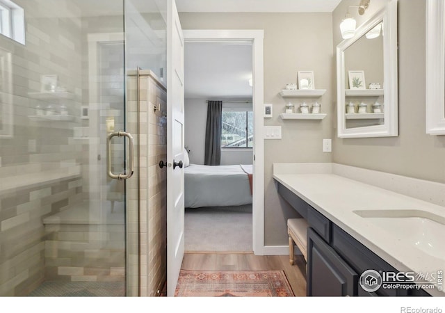 full bath with a shower stall, connected bathroom, wood finished floors, and vanity