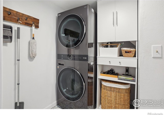 washroom featuring stacked washer and dryer and cabinet space