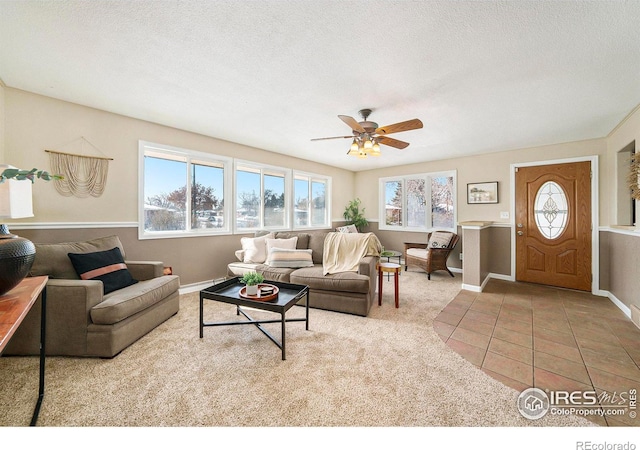 living room featuring baseboards, a textured ceiling, ceiling fan, and tile patterned flooring