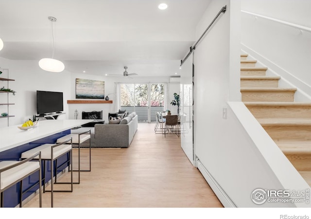 living area featuring ceiling fan, stairs, light wood-type flooring, a baseboard heating unit, and recessed lighting